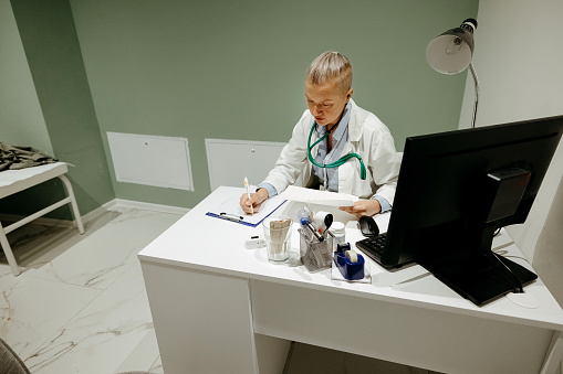 Doctor writing a medical prescription in his office