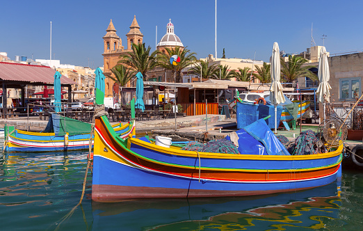 Traditional colorful wooden fishing boats luzzi in the village Marsaxlokk on a sunny day. Malta.