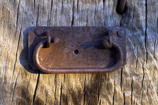 Rusty old door handle handle on old wooden door in vertical