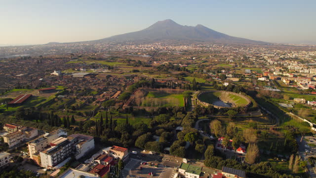 Pompeii ancient roman city with Vesuvius behind. Aerial dolly out at sunset
