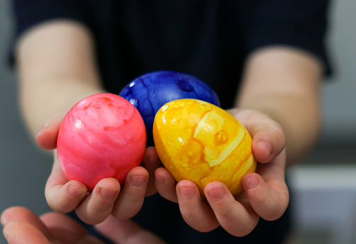Close up of little boy hands holding colored easter eggs, blurry background