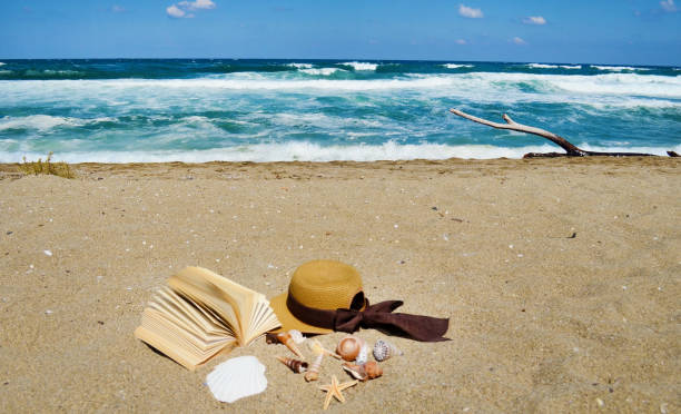 istock Book ,hat and seashells on the beach 2003353808