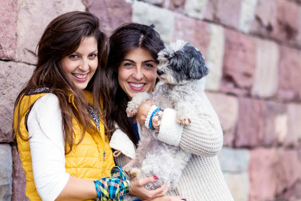 Sisters hugging  white  havanese dog  outdoor in the spring