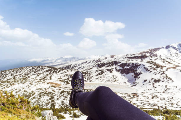 Personal perspective of woman  relaxing on top of Rila Mountain . Feet view . Travel vacations concept