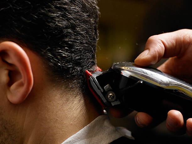 barber cutting man's hair, close-up of electric razor, side view - saç kesmek stok fotoğraflar ve resimler