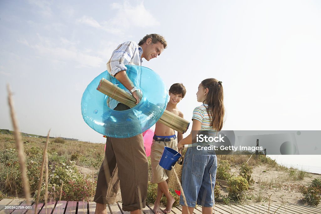 Padre y niños (7-9) en la ruta de transporte, esterilla para la playa y juguetes - Foto de stock de Entusiasmo libre de derechos