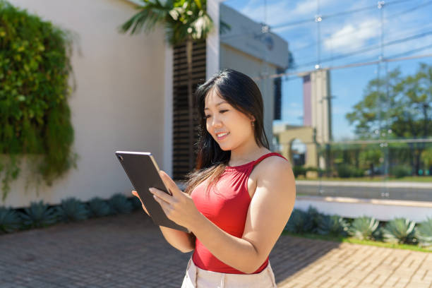 istock Young Asian woman using tablet in urban area 2003455304