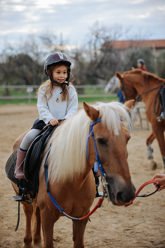 Ranch, happy and girl child on a horse to practice riding for a championship, competition or race. Happiness, animal and kid with smile practicing to ride a pony pet on a field or farm in countryside