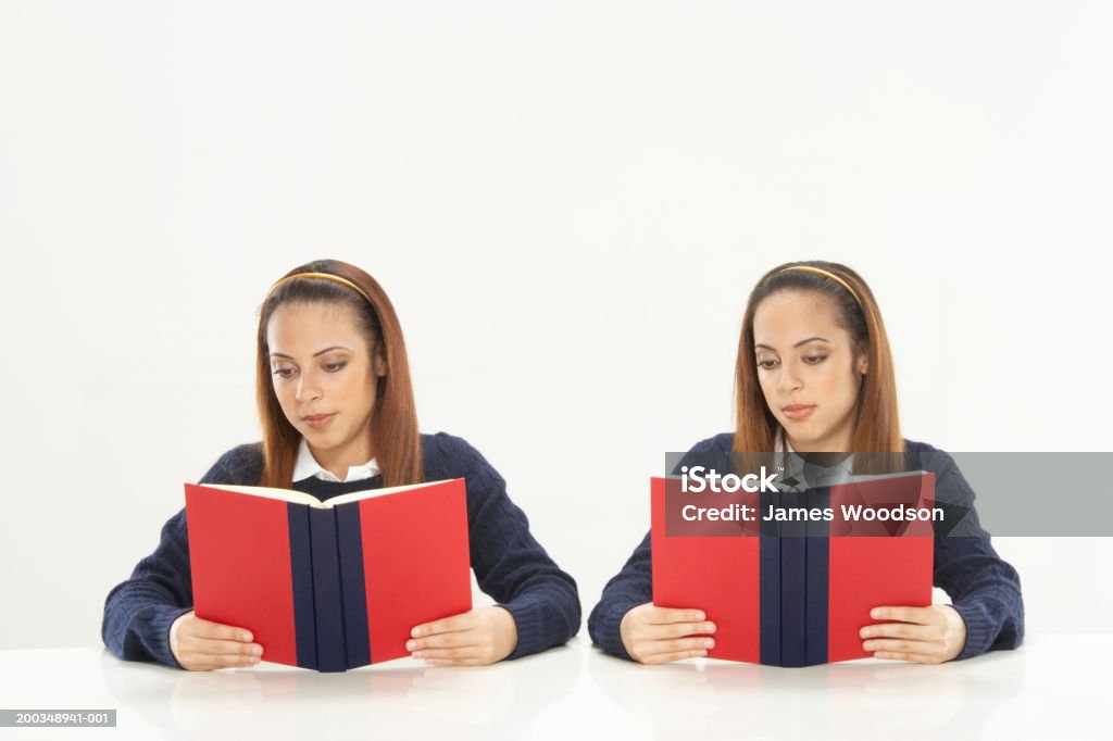 ツイン姉妹リーティング書籍、学生の制服を着ている - 双子のロイヤリティフリーストックフォト