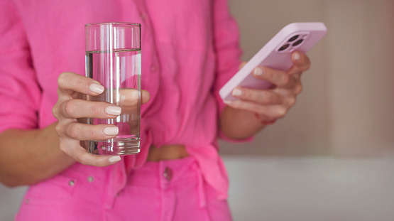 Woman drinking water with Water Reminder App on the Phone