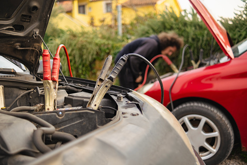 Young man putting a lot of effort to start and old car that hasn't been driven in a while