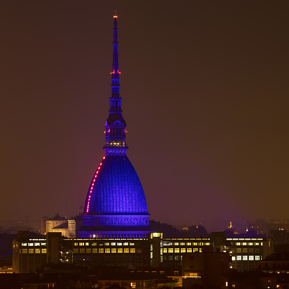 The cityscape of Turin, dominated by its landmark, the Mole Antonelliana, in a foggy winter night.