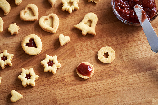 Filling homemade Linzer Christmas cookies with red marmalade