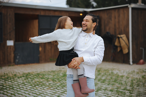 Happy young father and daughter having fun while running in autumn day at the park.