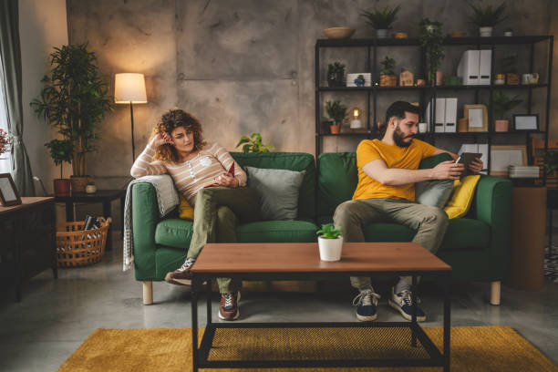 istock man and woman read book and use digital tablet at home on sofa bed 2003596404