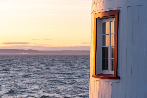 At the sunset, a window of the Lighthouse of L’Isle-Verte with the St Lawrence river in background (Notre-Dame-des-Sept-Douleurs, L’Isle-Verte, Quebec, Canada)