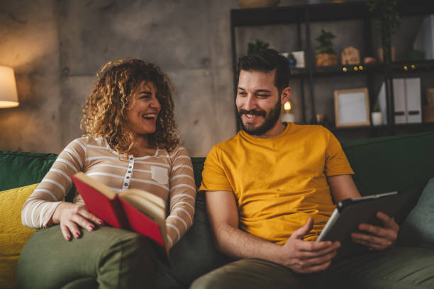 istock man and woman read book and use digital tablet at home on sofa bed 2003610437