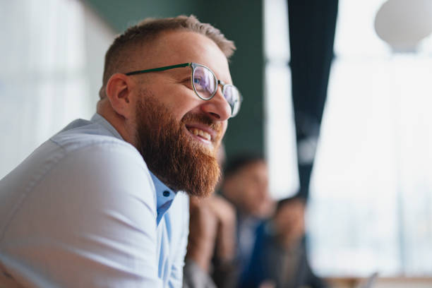 Smiling Bearded Man in Glasses at a Casual Business Meeting Happy professional man enjoying a conversation with colleagues group of people wearing eyeglasses stock pictures, royalty-free photos & images