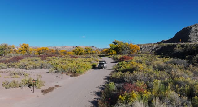 Offroading On Desert Landscape Near Bentonite Hills In Utah, USA. aerial pullback shot, slow motion