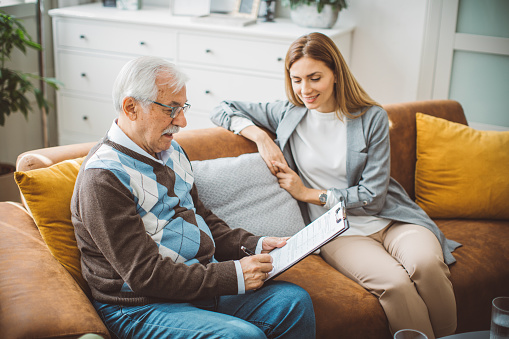 Senior men talking with female financial or real estate advisor at home.