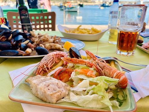 Grilled shrimps and mussels with salad on a plate. Tasty seafood salad with shrimps and mussels on the table