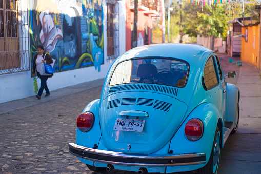 Xochimilco, Oaxaca, Mexico: A woman walks past a colorful mural in Xochimilco,  a neighborhood known for its murals. The neighborhood is also full of vintage VWs.