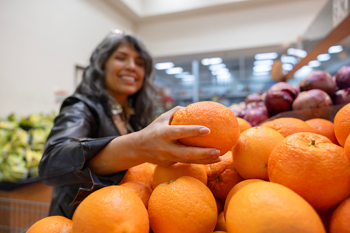 A Hispanic woman shopping at a grocery store for food.
