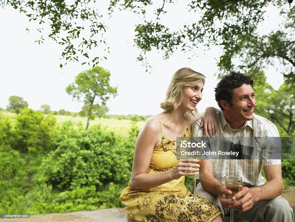 Coppia avendo un drink sulla terrazza, sorridente - Foto stock royalty-free di Alta società