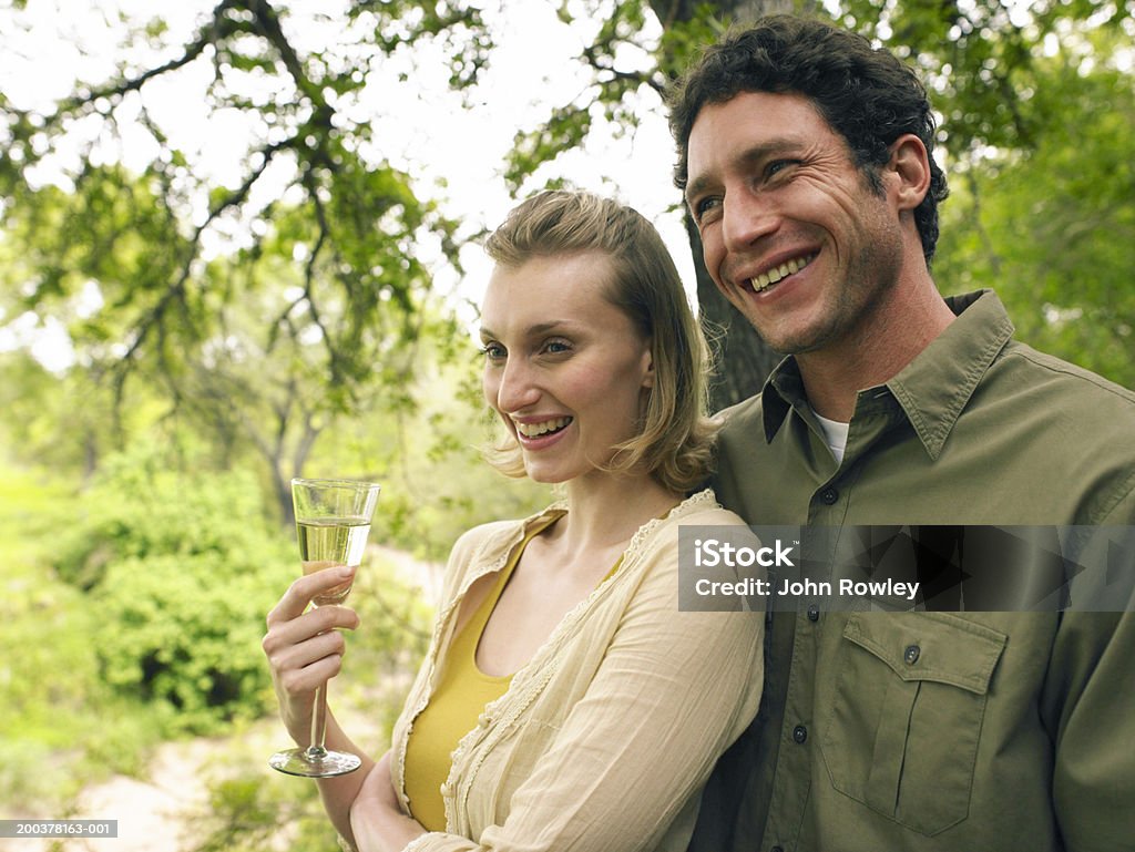 Pareja en el exterior, mujer agarrando una bebida, sonriendo, primer plano - Foto de stock de 30-34 años libre de derechos