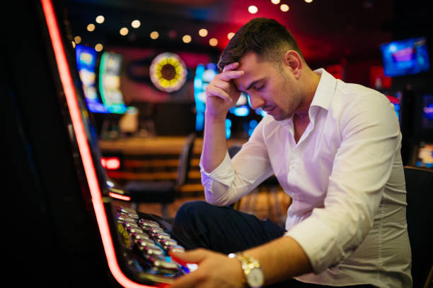 istock Young man loosing his money on a slot machine 2003806709