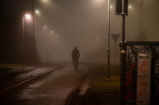 Stockholm, Sweden Jan 30, 2024 A bicyclist in silhouette at night on a foggy path.