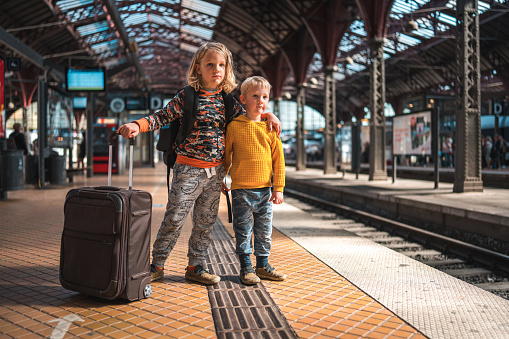 Ready for their train journey, two young Caucasian boys stand at the Copenhagen station, waiting to depart.