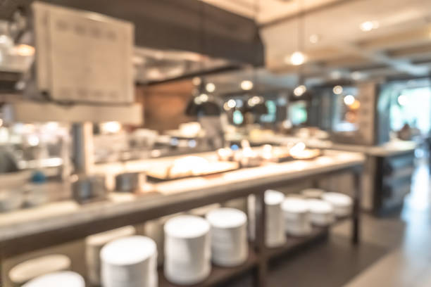 istock Buffet at hotel restaurant interior blur background with blurry open kitchen counter bar of food catering service business with chef staff cooking for breakfast, lunch or dinner meal 2003847905