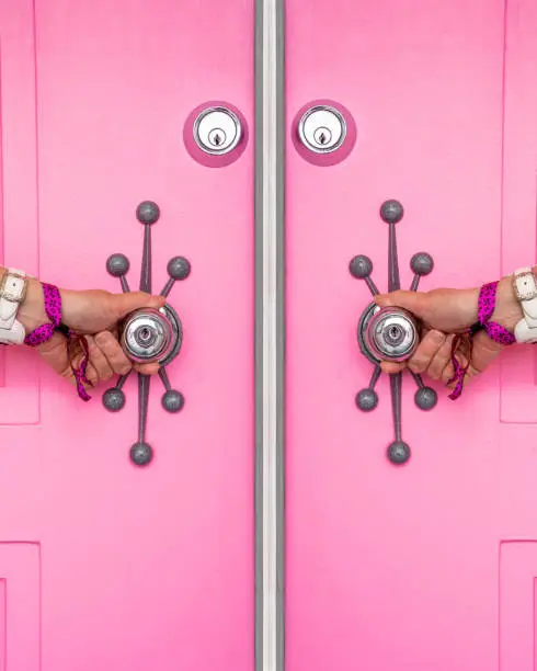 Pink door with a woman's hands holding the doorknobs in Palm Springs, California