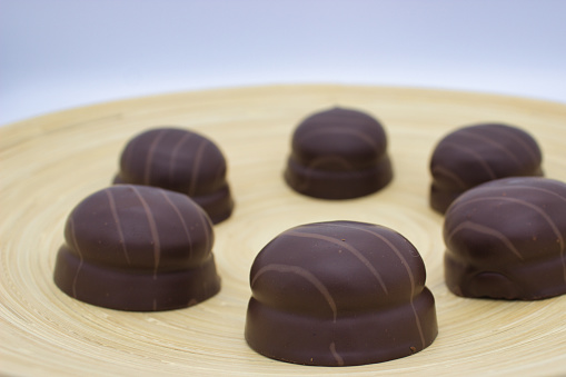 Artisan dark chocolate candies arranged on bamboo dish