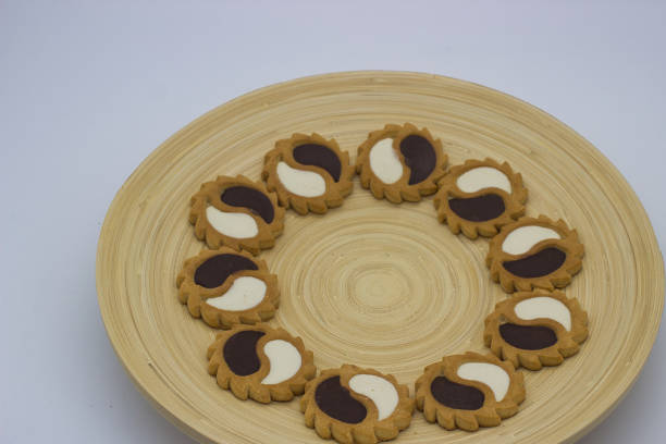 Half-moon shaped cookies with dual-colored icing on wooden plate