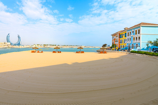 A sandy beach and colorful waterfront luxury residential apartments along the canals in the Venetian inspired Qanat Quartier, on the manmade Pearl Island in Doha Qatar