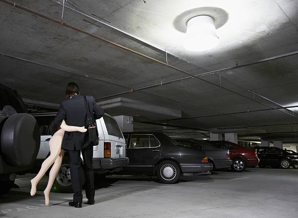 Young businessman carrying blow-up doll in parking garage, rear view  blow up doll stock pictures, royalty-free photos & images