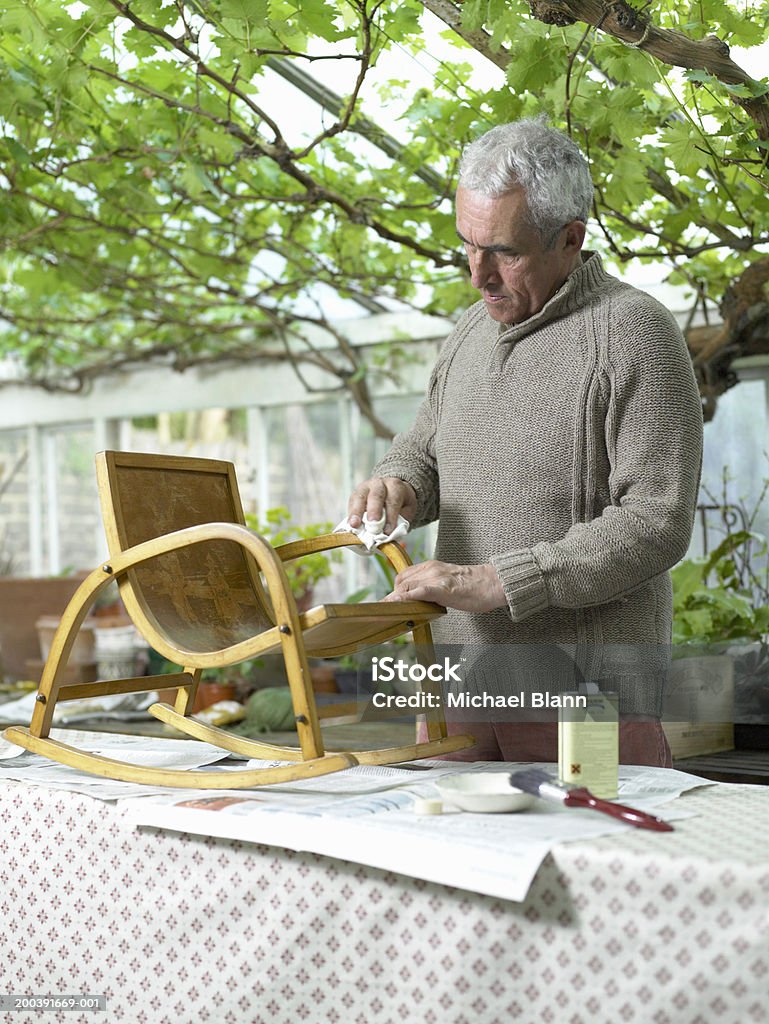 Старший мужчина varnishing стул в теплице - Стоковые фото На открытом воздухе роялти-фри