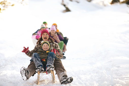 istock Mother and son (8-10) tobogganing in snow, family in background 200397284-001