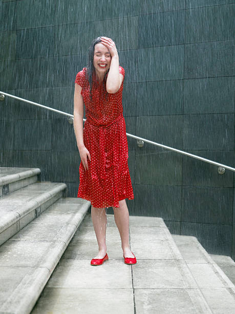 Young woman on steps in rain, hand resting on head, eyes closed  drenched stock pictures, royalty-free photos & images