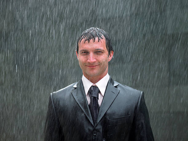 homme d'affaires debout sous la pluie, souriant, portrait, gros plan - mouillé photos et images de collection