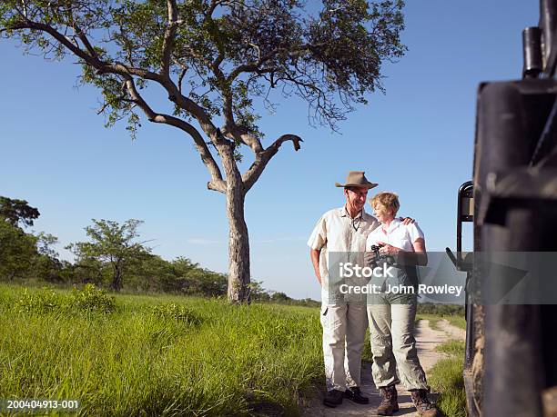 Couple By Jeep Woman Holding Binoculars Mans Arm Around Woman Stock Photo - Download Image Now