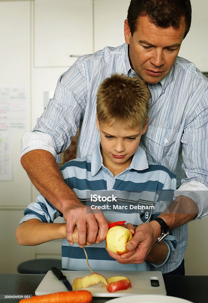 Père aide fils (10 à 12) peel pomme - Photo de Pomme libre de droits