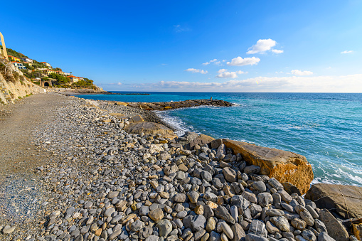 The rocky beach and coastline along the Mediterranean Sea below the hilltop medieval town of Cervo, Italy, in the Imperia province of the region of Liguria, along the Italian Riviera.