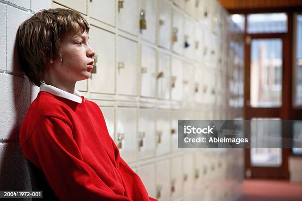 Schulkindnur Jungen Sitzt Im Korridor Schiefen Kopf Auf Wand Seite Stockfoto und mehr Bilder von Kind
