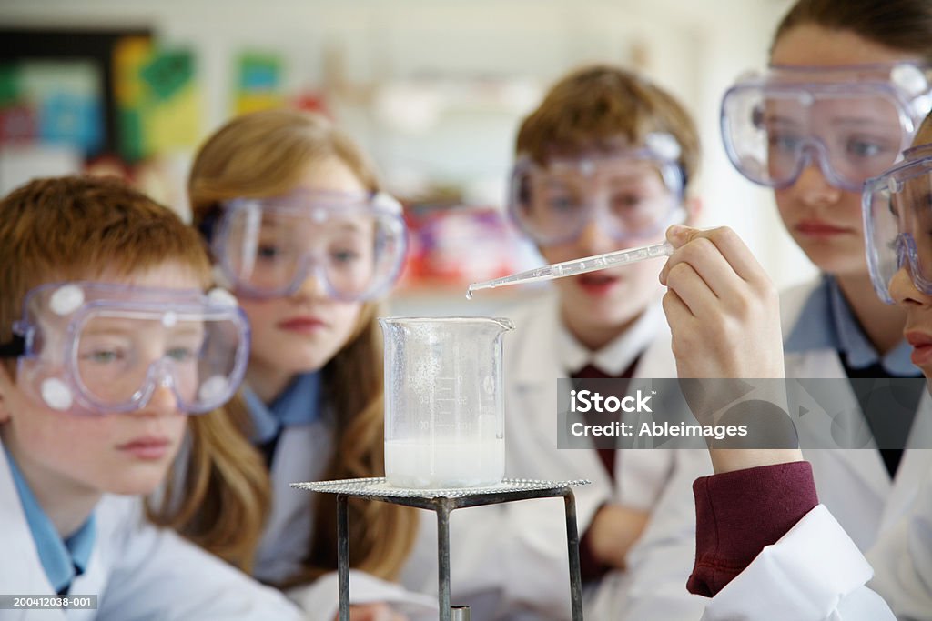 Pupils (11-13) wearing goggles watching experiment in science class  Chemistry Stock Photo