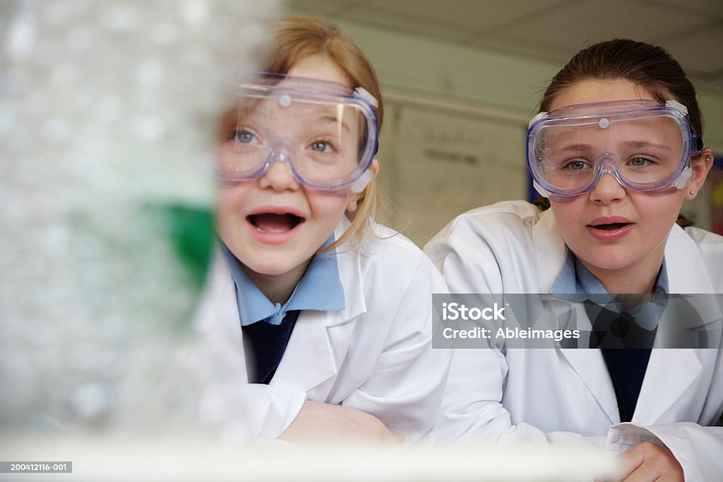 Two schoolgirls (11-13) watching experiment in science class Focus on girls. Child Stock Photo