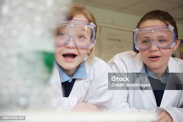 Two Schoolgirls Watching Experiment In Science Class Stock Photo - Download Image Now