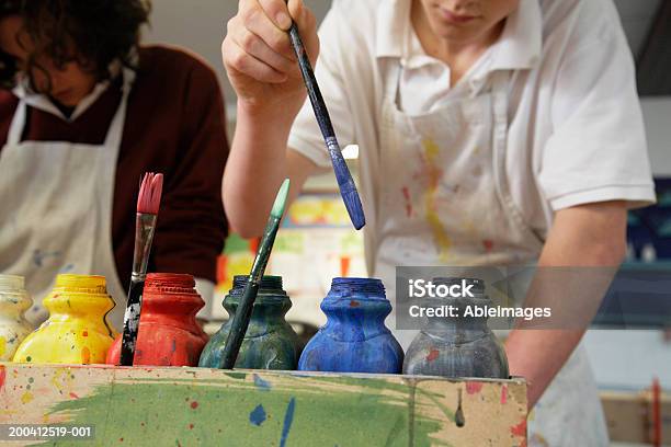 Maschio Studente Immergere Lo Spazzolino Nella Finestra Di Paint Bottiglia Mid Sectio - Fotografie stock e altre immagini di 14-15 anni